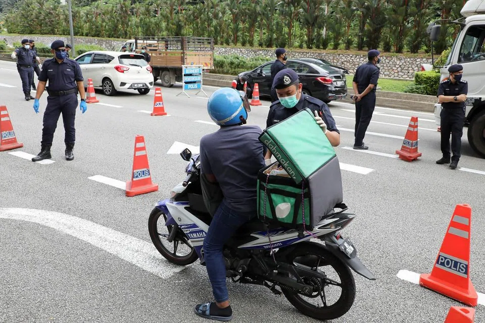 Pegawai polis memeriksa kenderaan di sekatan jalan semasa Perintah Kawalan Pergerakan (PKP), di tengah-tengah wabak penyakit Covid-19 yang meningkat di Malaysia. - Foto REUTERS