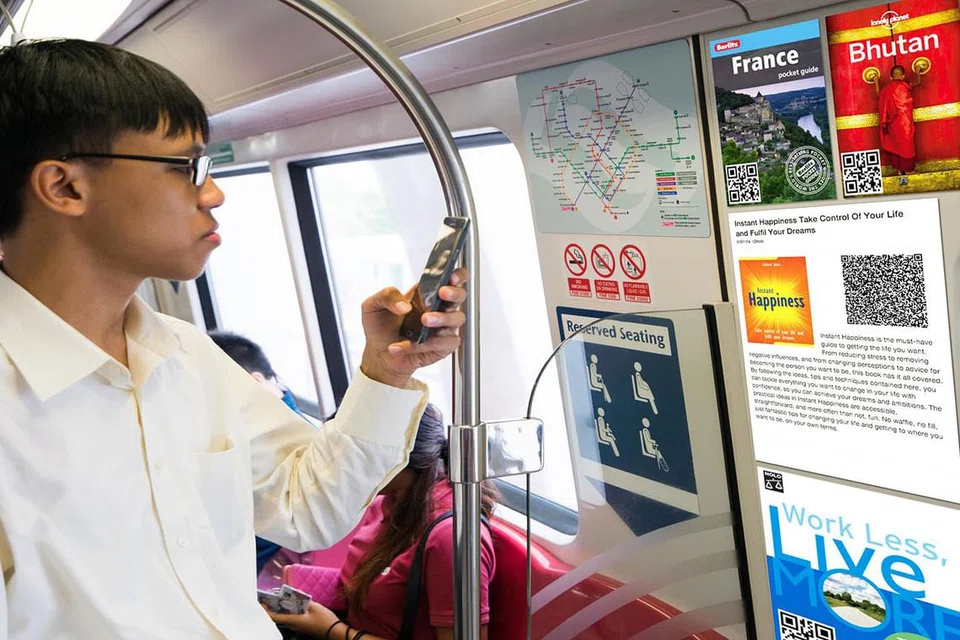 MEMUAT TURUN E-BUKU: Dengan inisiatif yang akan dilancarkan oleh NLB dan LTA, penumpang kereta api boleh menggunakan telefon bimbit mereka mengimbas kod QR bagi memuat turun e-buku menerusi aplikasi mudah alih NLB atau mendapatkan kandungan lain seperti esei pendek yang boleh dibaca semasa dalam kereta api. - Foto MCI