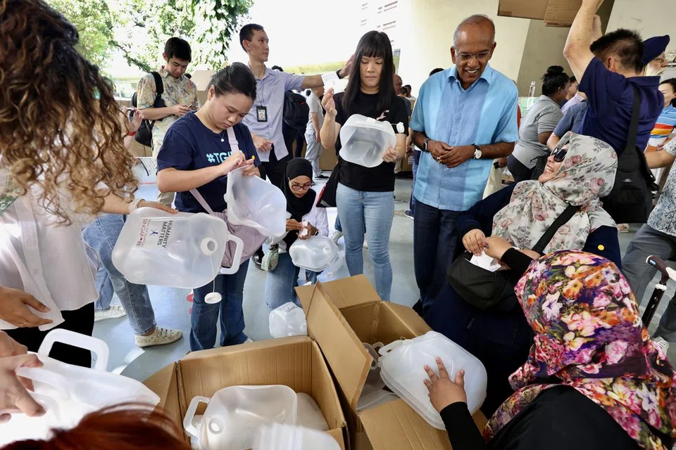 DEKATI RELAWAN: Menteri Ehwal Dalam Negeri merangkap Undang-Undang, Encik K. Shanmugam (berkemeja biru), mendekati beberapa relawan yang sedang membungkus bekalan keperluan kemanusiaan yang akan dihantar kepada mangsa di Gaza dalam satu acara anjuran pertubuhan Humanity Matters pada pagi Ahad.