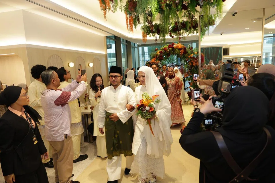 Ketiga-tiga pasangan pengantin diiringi paluan kompang ketika memasuki dewan sebelum acara memotong kek bersama.