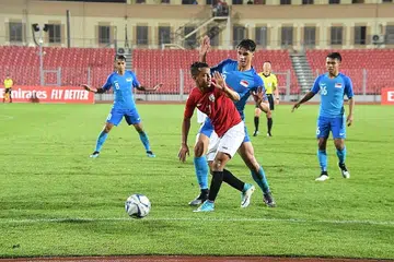 IKHSAN CEMERLANG: Ikhsan (tengah jersi biru) dihalang pemain Yaman (tengah, jersi merah) daripada merampas bola dalam kemenangan Singapura 2-1 ke atas Yaman di Stadium Sheikh Ali bin Mohammed Al Khalifa, Bahrain. - Foto BAHRAIN FA