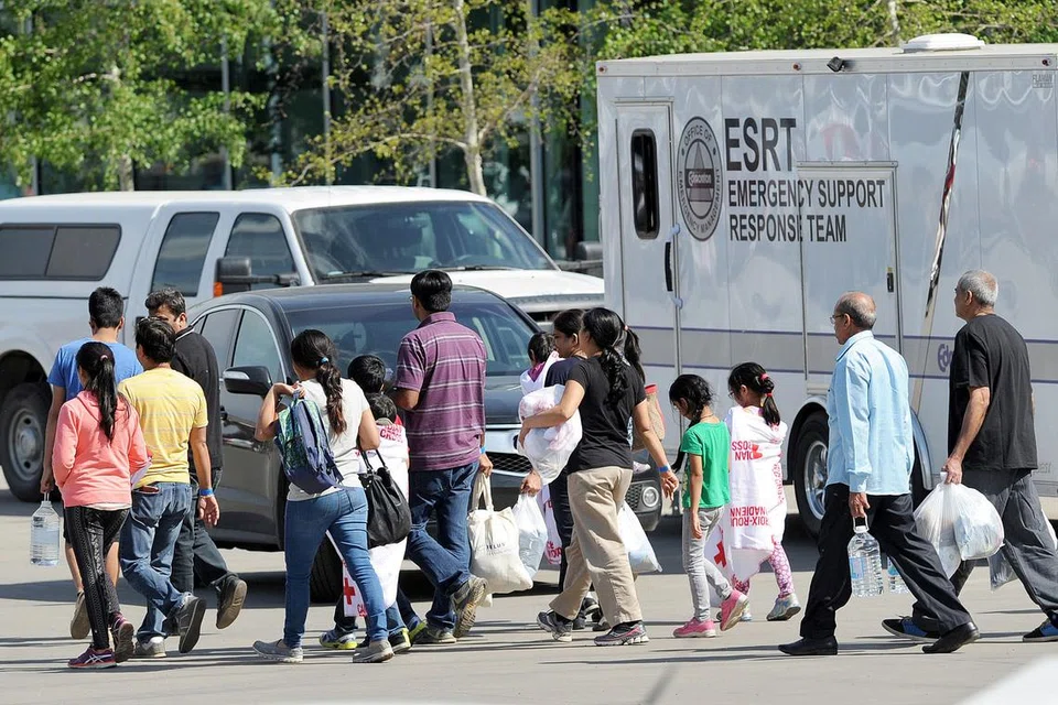 DAPATKAN BANTUAN: Penduduk dari Fort McMurray yang terpaksa berpindah beredar dari bangunan The Expo Centre sejurus mendapatkan bekalan makanan masing-masing. - Foto REUTERS 