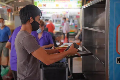 PULANGKAN DULANG ANDA: Seorang pelanggan mengembalikan dulang serta pinggan dan sisa makanannya di Pasar dan Pusat Makanan Yuhua Village pada 21 Jun 2021. - Foto BH oleh MARK CHEONG