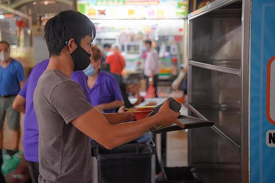 PULANGKAN DULANG ANDA: Seorang pelanggan mengembalikan dulang serta pinggan dan sisa makanannya di Pasar dan Pusat Makanan Yuhua Village pada 21 Jun 2021. - Foto BH oleh MARK CHEONG