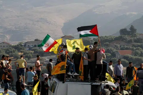 SEDIA MEMBANTU: Gambar yang dirakamkan pada 14 Mei lalu menunjukkan penyokong Hezbollah di Lebanon mengibarkan bendera mereka (kuning) dan bendera Iran (kiri) dan Palestin (kanan) semasa bantahan antiIsrael di kawasan selatan Khiam yang bersempadankan Israel, menghadap bandar Metula di utara Israel. - Foto AFP