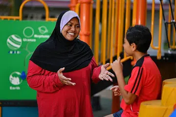 'MUMMY JAN': Cik Diljan berinteraksi dengan Izmi Muhaimin Hamzar, 11 tahun, pelajar program tuisyen percuma yang dimulakan Cik Diljan di bawah Yup. Program menyeluruh itu bertujuan memberi sokongan kepada belia dan kanak-kanak kurang bernasib baik dengan melibatkan keluarga serta jiran mereka sekali. - Foto BH oleh CHONG JUN LIANG