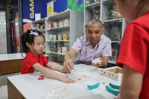 Pengasas bersama Origame, pereka permainan papan tempatan, Dr Daryl Chow, bermain bersama pasangan kembar berusia enam tahun, Ellery (kiri) dan Averyl Ng, di ruang Comics and Games Library pada 30 April lalu.
