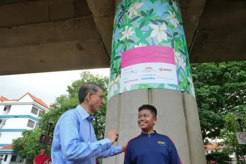 Pemangku Menteri Bertanggungjawab bagi Ehwal Masyarakat Islam serta Anggota Parlimen bagi GRC Marine Parade-Braddell Heights (Kembangan), Profesor Madya Dr Muhammad Faishal Ibrahim (kiri) beramah mesra bersama Nur Muhammad Darwish Mohammad Ridzwan, 14 tahun, salah seorang daripada 12 pelajar MINDS Towner Gardens School (TGS) yang menyumbang kepada penghasilan pemasangan seni awam Trainforest di stesen MRT Kembangan.