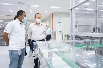 SOKONG AMBIL PEKERJA SETEMPAT: Dr Tan bersama Encik Faidzal yang merupakan antara pekerja baru yang diambil Alcon Singapore dengan sokongan JGI semasa lawatannya ke syarikat yang khusus menghasilkan produk penjagaan mata itu. - Foto MOM