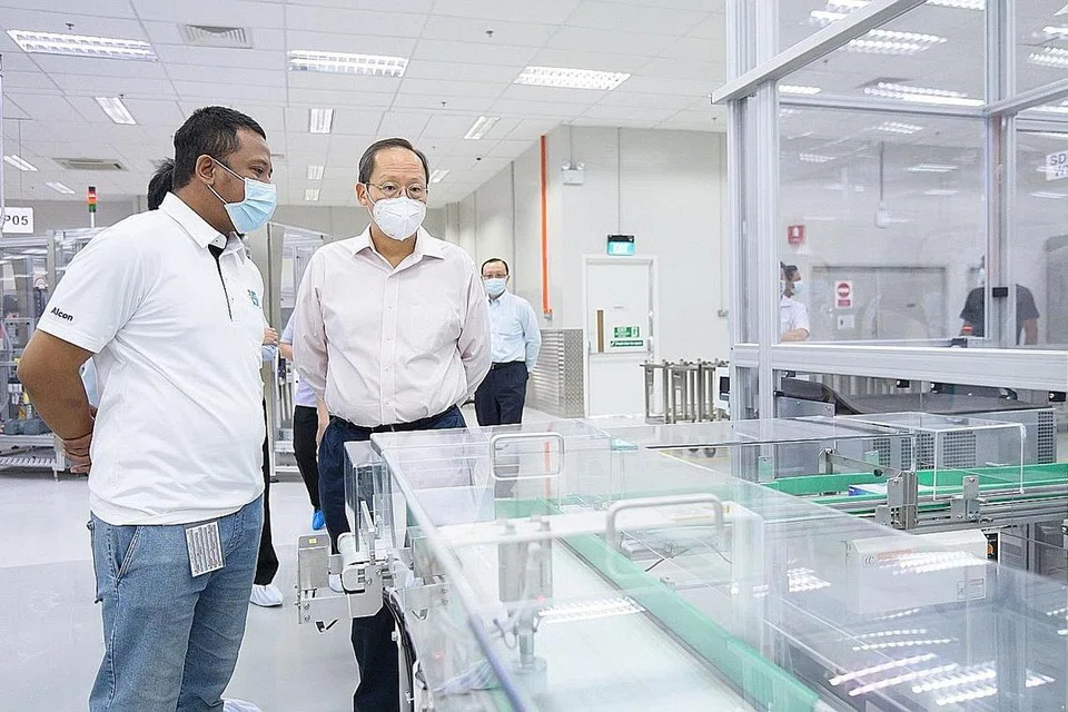 SOKONG AMBIL PEKERJA SETEMPAT: Dr Tan bersama Encik Faidzal yang merupakan antara pekerja baru yang diambil Alcon Singapore dengan sokongan JGI semasa lawatannya ke syarikat yang khusus menghasilkan produk penjagaan mata itu. - Foto MOM