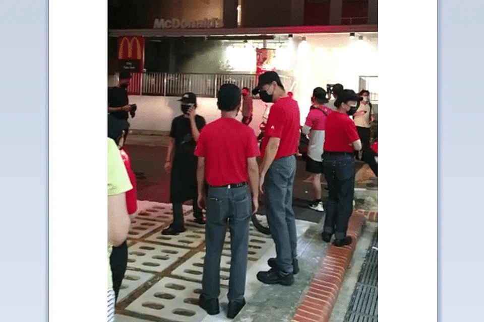 Orang ramai termasuk kakitangan McDonald's berkumpul di luar cawangan restoran tersebut di Tampines St 23 dek kebakaran yang berlaku di sana pada sekitar 9.50 malam, 12 April. - Tangkap layar video