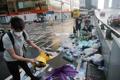 SISA RUSUHAN: Beberapa orang membersihkan jalan yang penuh dengan sampah-sarap yang ditinggalkan para penunjuk perasaan di Hongkong semalam. - Foto REUTERS