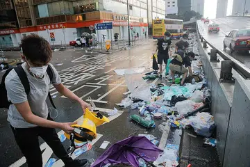 SISA RUSUHAN: Beberapa orang membersihkan jalan yang penuh dengan sampah-sarap yang ditinggalkan para penunjuk perasaan di Hongkong semalam. - Foto REUTERS