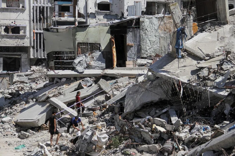 Penduduk Gaza  berjalan di sebuah kawasan yang musnah akibat serangan tentera Israel di Beit Lahia, utara Gaza, pada 12 Jun, sementara rundingan bagi gencatan senjata antara Israel dengan Hamas masih belum mencapai persetujuan.