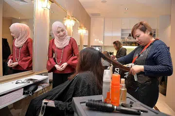 BERKHIDMAT KEPADA WARGA BARAT SINGAPURA: Cik Rozza (bertudung) berharap dapat memenuhi keperluan wanita, khususnya Muslimah, di serata negara menerusi Karva. - Foto M.O. SALLEH