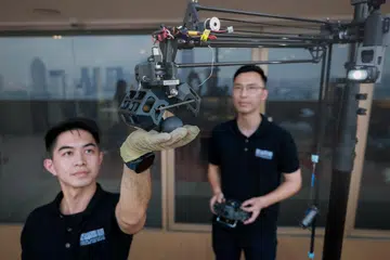Zamil penyelidik Universiti Teknologi dan Reka Bentuk Singapura (SUTD), Encik Shawndy Michael Lee (kiri), dan penolong penyelidik kanan, Encik Liu Jingmin, menunjukkan peranti yang digunakan untuk mengambil telur burung falkon peregrine di bangunan Pusat OCBC pada 15 November.