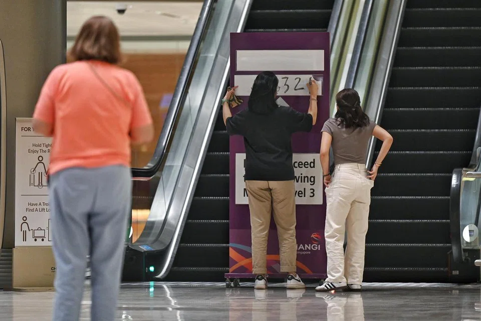 Seorang pegawai lapangan terbang dilihat menulis SQ321 diikuti dengan arahan untuk pergi ke galeri meninjau di lantai tiga, Terminal 2 Lapangan Terbang Changi.