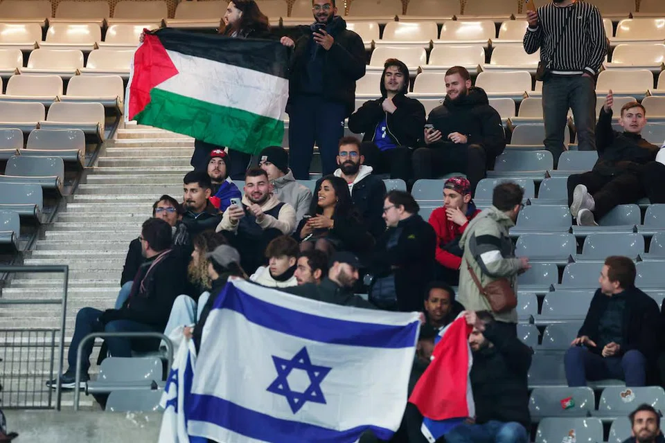 Penonton mengibarkan bendera Palestin dan Israel semasa kejohanan Liga Negara-Negara Kesatuan Persatuan Bola Sepak Eropah (Uefa) pada 14 November di Paris.