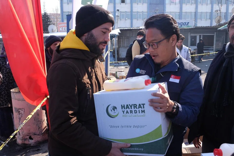 HULUR BANTUAN: Pengurus Kanan Program Antarabangsa di Mercy Relief, Encik Khairulnizam Massuan (kanan), memberikan pakej bantuan mengandungi sabun, syampu dan barangan keperluan asas lain kepada warga Turkey di pusat pengagihan bantuan di Elbistan, Kahramanmaras, yang terletak di selatan Turkey. - Foto BH oleh IZWANDI AZMAN