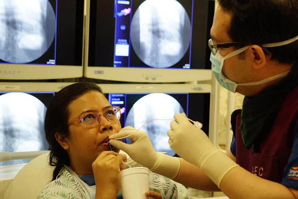 KURANGKAN BERAT BADAN TANPA PEMBEDAHAN: Dr Lim Chin Hong (kanan) membantu seorang pesakitnya, Cik Nur Shahida Suhaimi, semasa prosedur yang dikenali sebagai 'ingestible gastric balloon' pada Jun lalu.