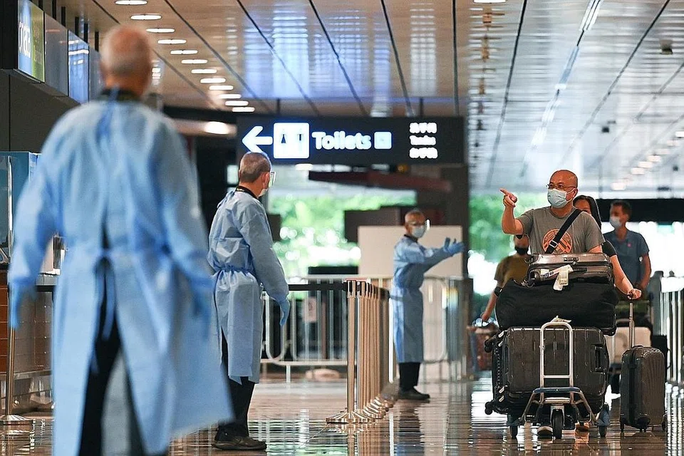 DISAMBUT DENGAN LANGKAH KESELAMATAN: Antara penumpang penerbangan SQ329 dari Belanda yang tiba di Lapangan Terbang Changi pagi semalam. Setiba di sini, mereka antara lain diarah menjalani ujian Reaksi Rantaian Polimerase (PCR) oleh kakitangan lapangan terbang yang memakai pakaian perlindungan, pelitup dan sarung tangan. - Foto BH oleh LIM YAOHUI