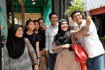 TEMPUHI TUGAS BARU DENGAN SABAR: Cik Yuliza Wati Mohamad Yusoff (memegang telefon bimbit) bersyukur rancangan menjadi pekerja sosial pada usia 40-an tahun disokong (dari kiri) ibunya Hajah Zainon Mohd Yusoff, anaknya Ummu Kalthum, Siti Zahrah, Zainab dan Md Zulfikar (kanan), serta suami Encik Iskandar Wachi. - Foto M.O. SALLEH