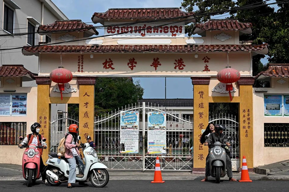 Gambar yang dirakam pada 9 April 2025 ini menunjukkan pelajar menunggang motosikal melepasi sekolah bahasa Cina di Sihanoukville. Pakar bahasa Kemboja, Encik Um Keangseng, membuka sekolah itu di bandar kelahirannya selepas melihat permintaan yang semakin meningkat.