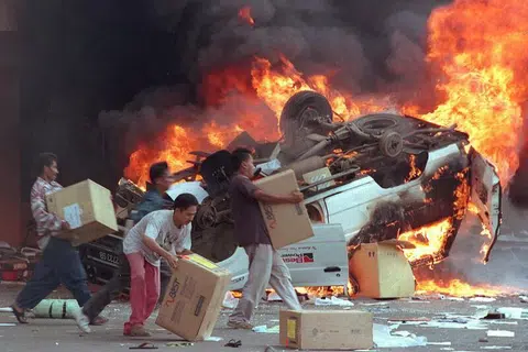 Kumpulan perusuh Indonesia membakar kereta dan perniagaan Cina ketika mereka merompak kedai di Jakarta pada 14 Mei 1998.