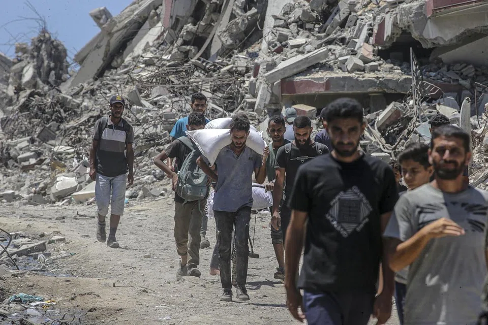 Penduduk Palestin membawa kampit tepung di sepanjang Jalan Rashid di barat Jabalia, utara Jaluran Gaza, pada 20 Julai 2025. Menurut Kementerian Kesihatan Palestin di Gaza, sekurang-kurangnya 90 orang terbunuh ketika cuba mendapatkan bantuan kemanusiaan di kawasan Zikim, utara Gaza.