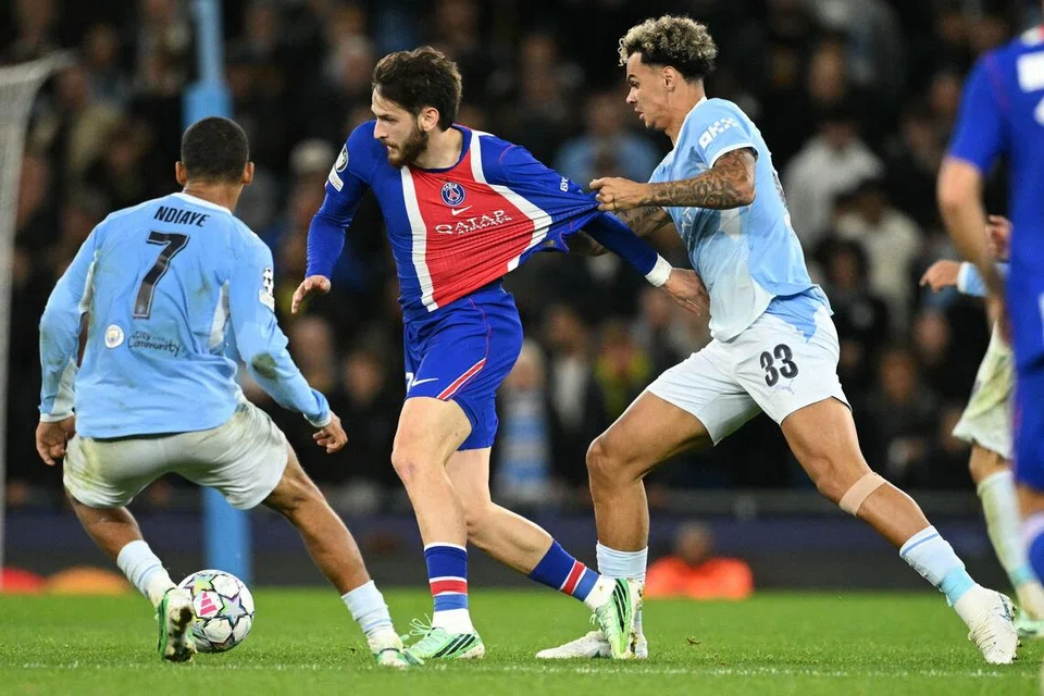 Penyerang Paris Saint-Germain (PSG), Khvicha Kvaratskhelia (tengah), cuba meloloskan diri daripada dua pemain Manchester City, Nico O'Reilly (kanan) dan Iliman Ndiaye.