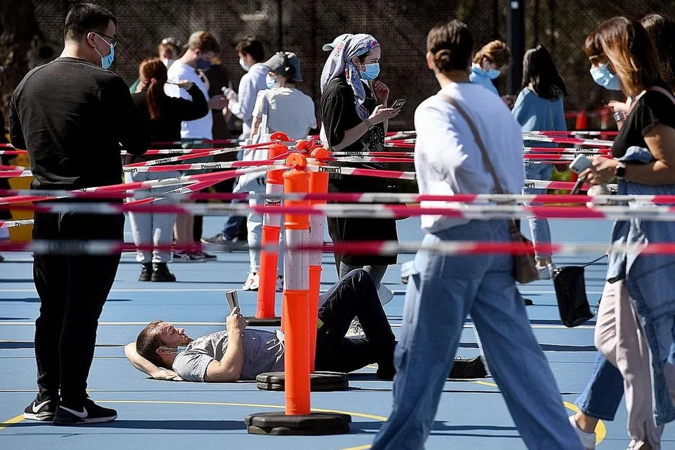 TUNGGU VAKSINASI: Seorang lelaki membaca buku sedang beliau menunggu bagi mendapatkan vaksinasi di pusat vaksinasi Covid-19 di Melbourne semalam. - Foto AFP