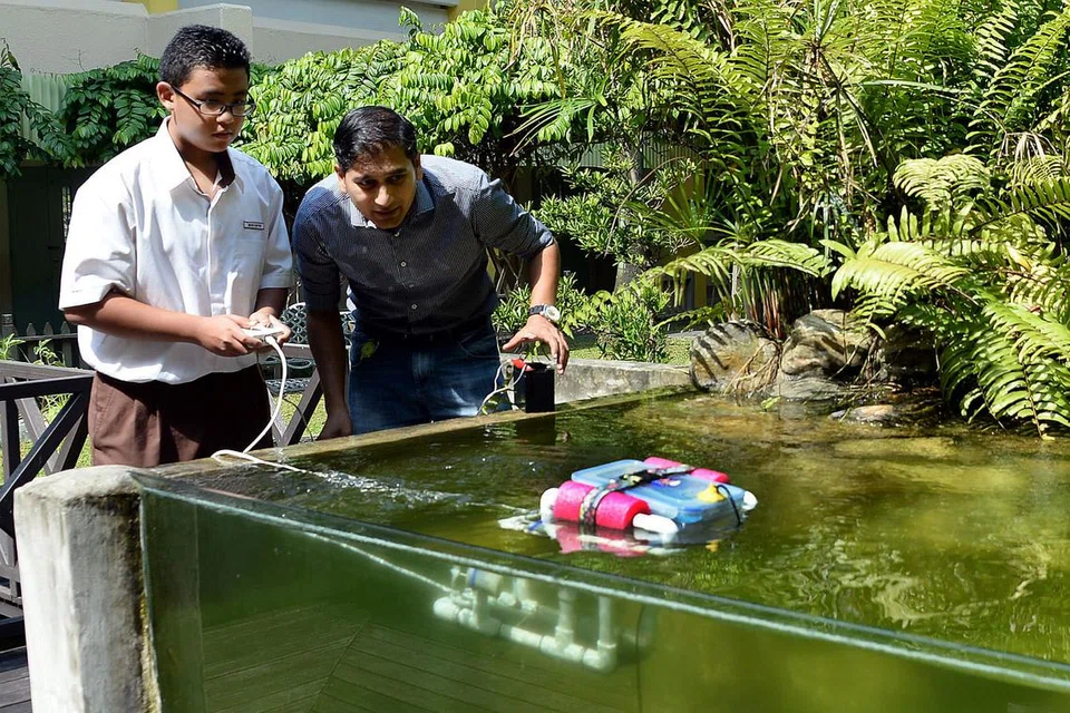 PUPUK MINAT PADA TEKNOLOGI: Encik Sirajutheen dan muridnya, Muhd Rayyan Samsul Kamat, mencuba robot yang direka pelajar menengah dua bagi mengesan mutu air di Sekolah Menengah Bukit View, Bukit Batok Street 21.