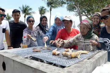 TRADISI KELUARGA: Cik Salmah (tiga dari kanan) tidak pernah melepaskan peluang berkumpul bersama keluarga di tepi pantai pada hari cuti. Mereka sekeluarga ditemui berbarbeku di Pantai Changi pada cuti panjang Tahun Baru Cina. - Foto-foto TAUFIK A. KADER
