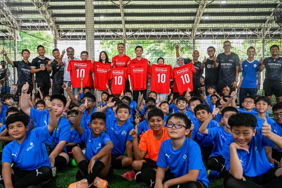 Peserta bergambar bersama tetamu undangan Menteri Negara (Kebudayaan, Masyarakat dan Belia merangkap Perdagangan dan Perusahaan), Encik Alvin Tan (tengah memegang jersi merah) serta jurulatih dan ketua badan bantu diri. Sekitar 80 kanak-kanak menyertai Kem Bola Sepak anjuran empat badan bantu diri setempat yang diadakan pada 12 dan 13 Jun di Kick Off! Kovan. 