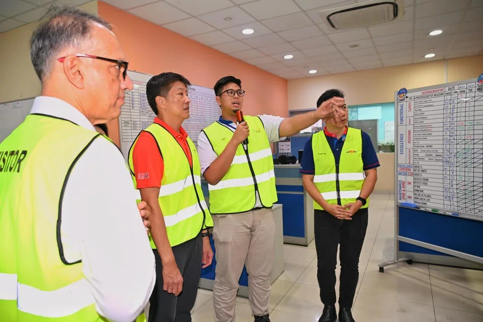 Encik Muhammad Faiz Kifliputra Azmi Kifrawi (dua dari kanan) menjelaskan cara komunikasi dalaman yang baru kepada Setiausaha Agung NTUC, Encik Ng Chee Meng (tiga dari kanan), semasa sesi melawati Pusat Pengagihan Benoi (BNDC) pada 29 Oktober.