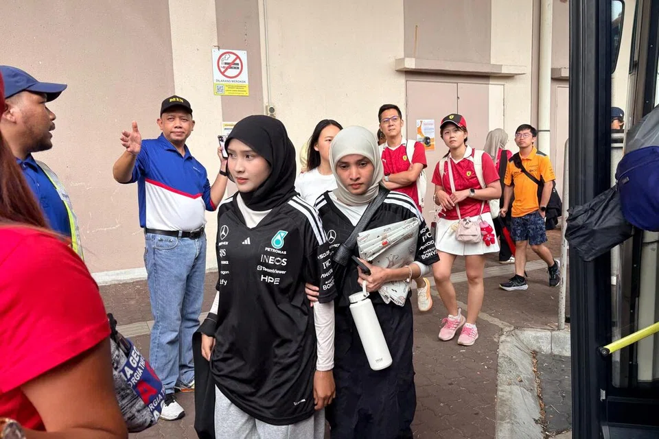 Ketua Penyelaras Tempat Mengambil Penumpang di Mitsui Outlet Park, Encik Sarifuddin Saidin (bertopi biru, dua dari kiri) membantu pengunjung perlumbaan Formula 1 Grand Prix (GP) Bahrain di Litar Antarabangsa Sepang Petronas (SIC), Selangor, pada 4 Oktober.