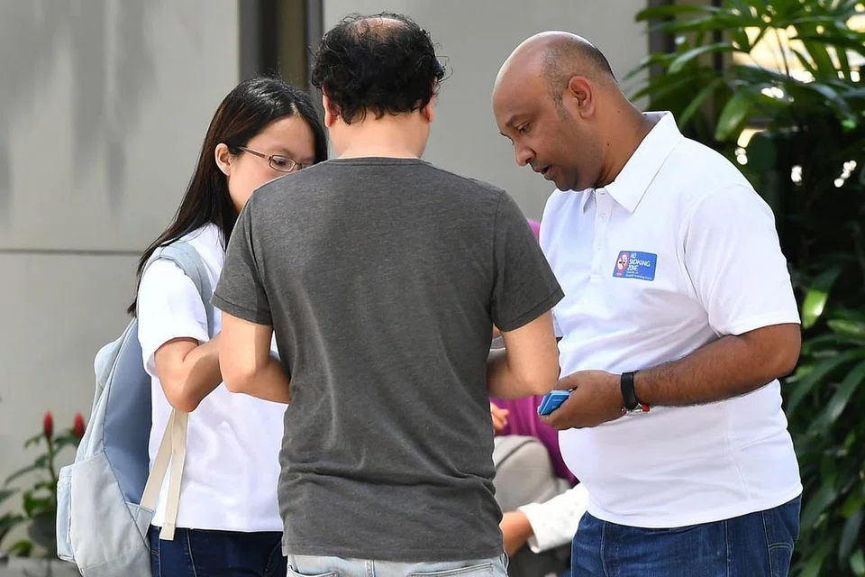 NASIHATI PEROKOK: Pegawai NEA (berbaju polo putih) mendekati lalu menasihatkan perokok yang didapati merokok di luar kawasan merokok ditetapkan. Mereka juga mengedarkan risalah senarai kawasan merokok. - Foto BH oleh LIM YAOHUI