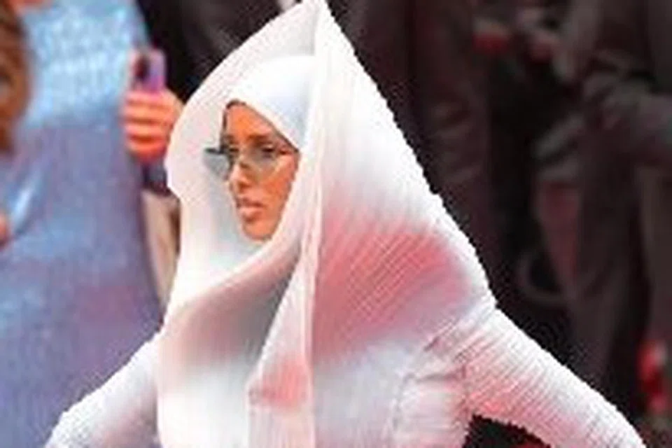 Model keturunan Somalia, Rawdah Mohamed, memperagakan gaun biru pastel menyerupai arca yang menampilkan lipatan rumit yang berlilit  seperti gelombang. 