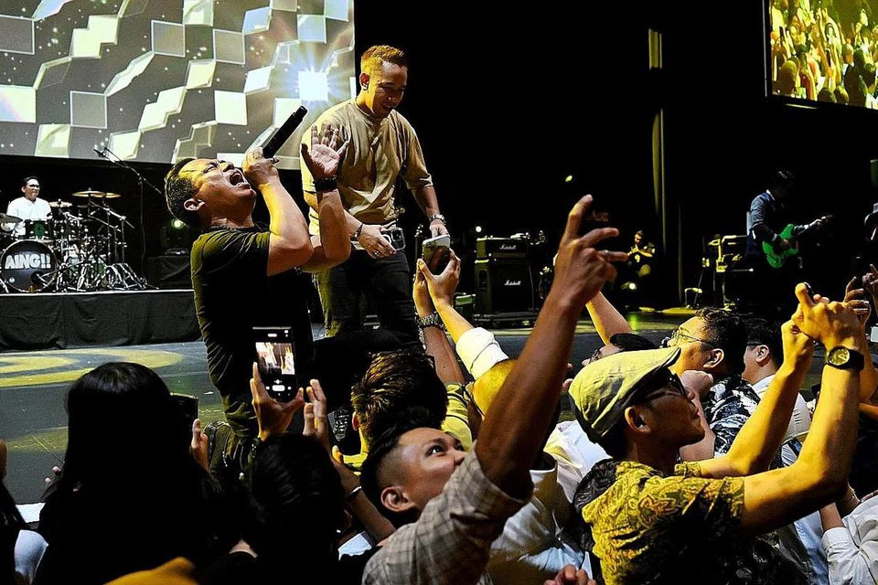 SERONOK BERDENDANG: Vokalis kumpulan Wali Band, Faank (kiri) yang ditemani penganjur konsert dan penghibur Singapura, Sufi Rashid (kanan), berinteraksi dengan penonton yang bergambar spontan dalam konsert, Cari Jodoh, pada Sabtu. - Foto BH oleh KHALID BABA