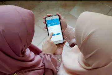 SALING MEMBANTU: Cik Khairiyah (kiri) membantu ibunya, Cik Jamilah (kanan), semasa menggunakan aplikasi pembayaran tanpa wang tunai. - Foto ihsan KHAIRIYAH ANWAR
