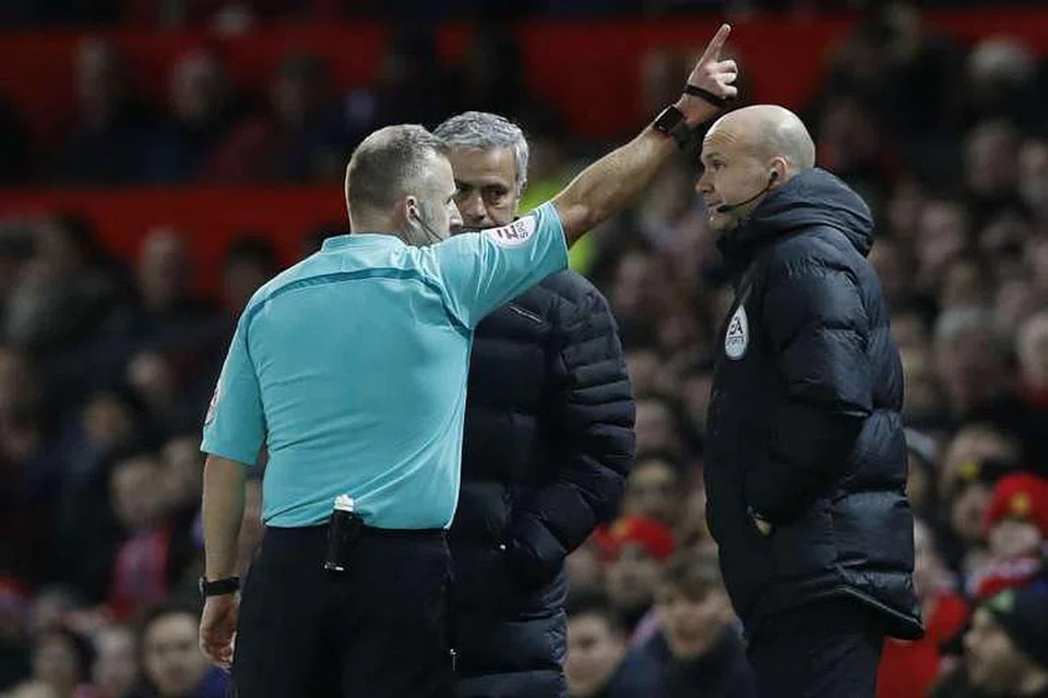 Pengurus Manchester United Jose Mourinho (menghadap kamera) dihantar ke tempat duduk penonton oleh pengadil Jonathan Moss. 