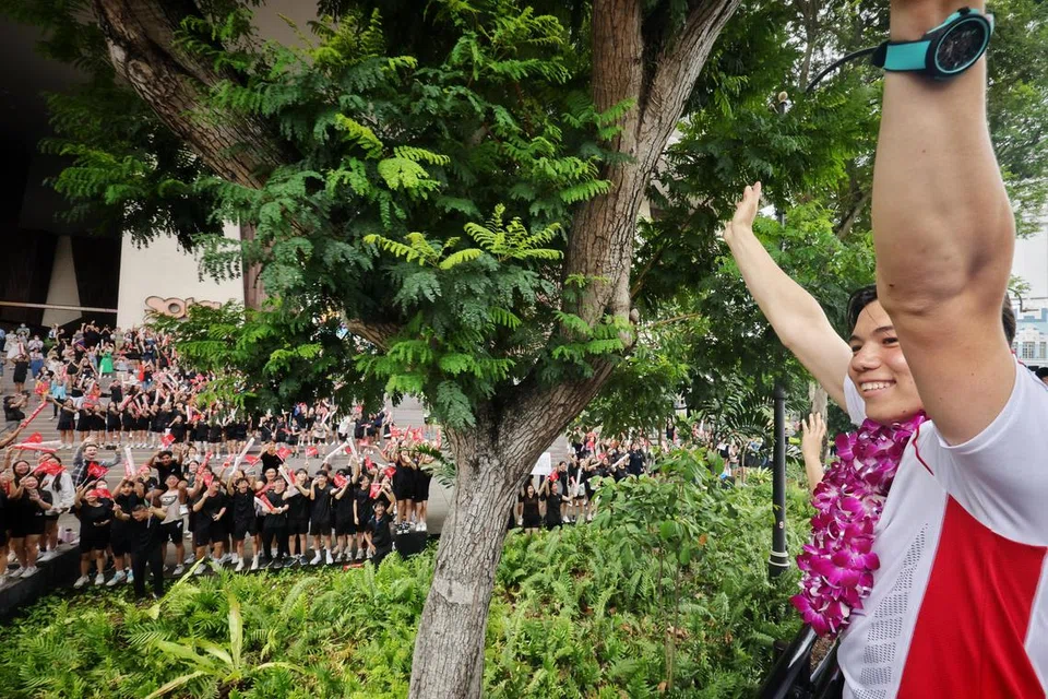 Atlet luncur lelayang, Maximilian Maeder bersama rakan-rakan Olimpik lain (terselindung) melambai kepada para pelajar Sekolah Seni Singapura (Sota) semasa perarakan sambutan One Team Singapore pada 14 Ogos.