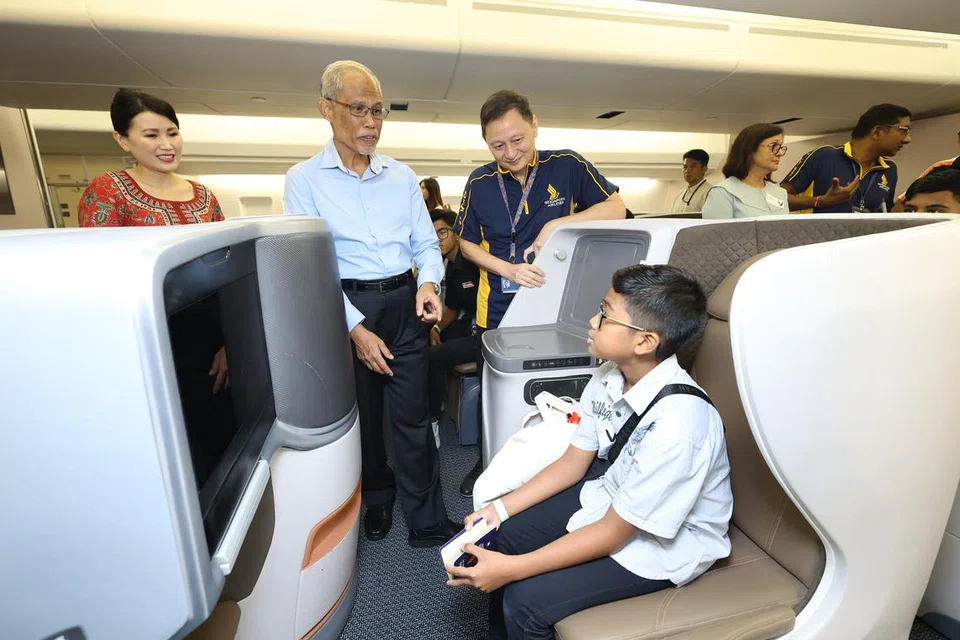 TINJAU KABIN PESAWAT: Menteri Pembangunan Sosial dan Keluarga, Encik Masagos Zulkifli Masagos Mohamad (kemeja biru) dan Ketua Pegawai Eksekutif SIA, Encik Goh Choon Phong (berbaju polo) kelihatan berinteraksi dengan salah seorang peserta lawatan dalam model kabin Kelas Bisnes.