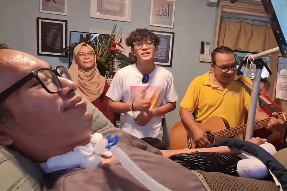 TERAPI MUZIK: Dendangan lagu Lovehunters 'Blues Untuk Rakyat' oleh Ayman Naufal (tengah) dan Asiyah Sinnan (kiri), dengan petikan gitar Pa'Mol (kanan) dan gendangan cajón Jalil 'Ajay' (terlindung), semasa mereka berkunjung ke rumah Riz Sunawan, untuk menemani dan menghiburkannya. Riz menghidap penyakit penyakit saraf motor neuron (MND), yang lebih dikenali sebagai Amyotrophic Lateral Sclerosis (ALS). - Foto PRIHATIN SINGAPURA