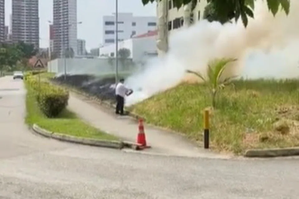 MENCABAR: Seorang lelaki kelihatan menggunakan pemadam api untuk memadamkan kebakaran berlaku di ruang lapang di Bukit Batok Street 22.