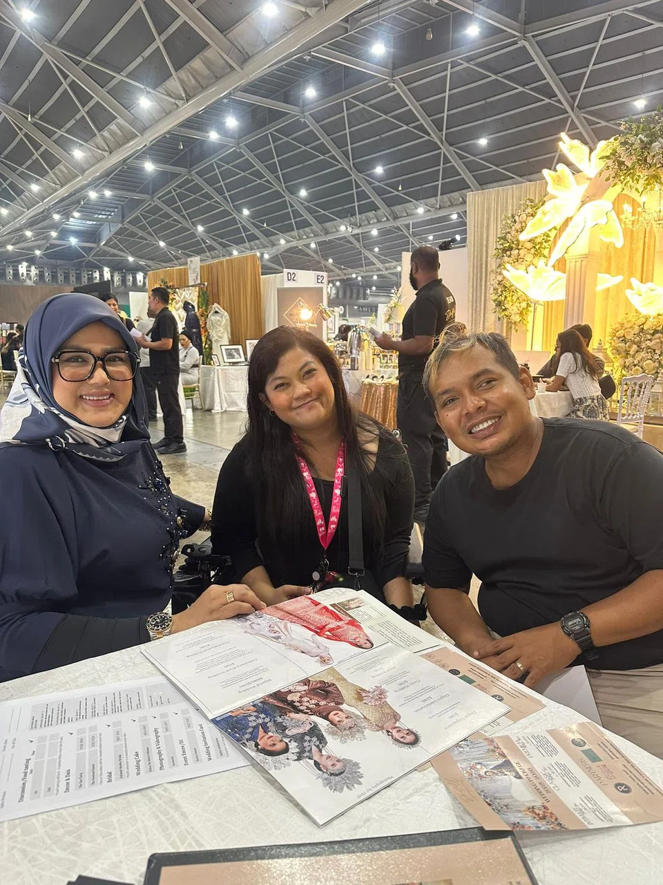 Bakal pengantin, Encik Herman Abdullah (kanan) dan Cik Roszana Ali (tengah) mengunjungi pameran pengantin untuk berjumpa dengan usahawan terkemuka, Cik Fatimah Mohsin (kiri).