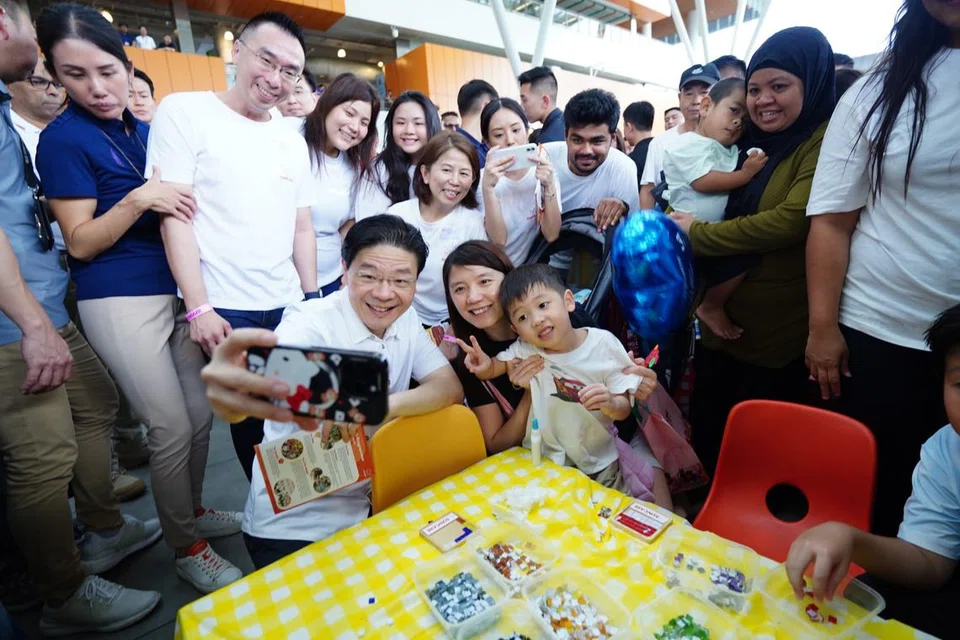 Perdana Menteri, Encik Lawrence Wong (berkemeja putih), bersama pengunjung di salah satu reruai aktiviti semasa majlis pelancaran One Punggol pada 8 September.