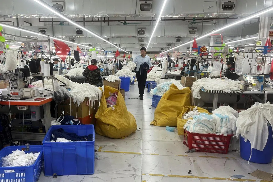 Pekerja-pekerja kilang menjalankan tugas di barisan pengeluaran di sebuah kilang pakaian di daerah Panyu, Guangzhou, wilayah Guangdong, China pada 1 April 2025.