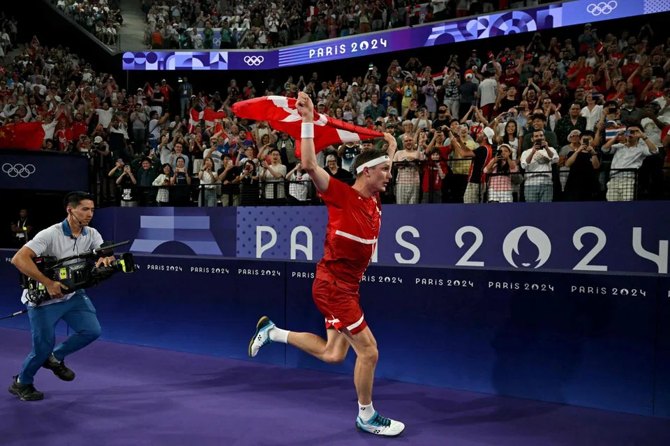 Viktor Axelsen berlari sekeliling gelanggang dengan bendera Denmark selepas beliau memenangi final perseorangan lelaki Olimpik pada 5 Ogos.