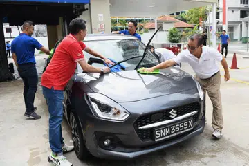 CUCI KERETA AMAL: Encik Seah Kian Peng, CEO Kumpulan NTUC Enterprise, dan Speaker Parlimen (pertama dari kanan), bersama pasukan pengurusan FairPrice, Cheers and Children’s Aid Society serta sukarelawan yang mengambil bahagian dalam aktiviti mencuci kereta.